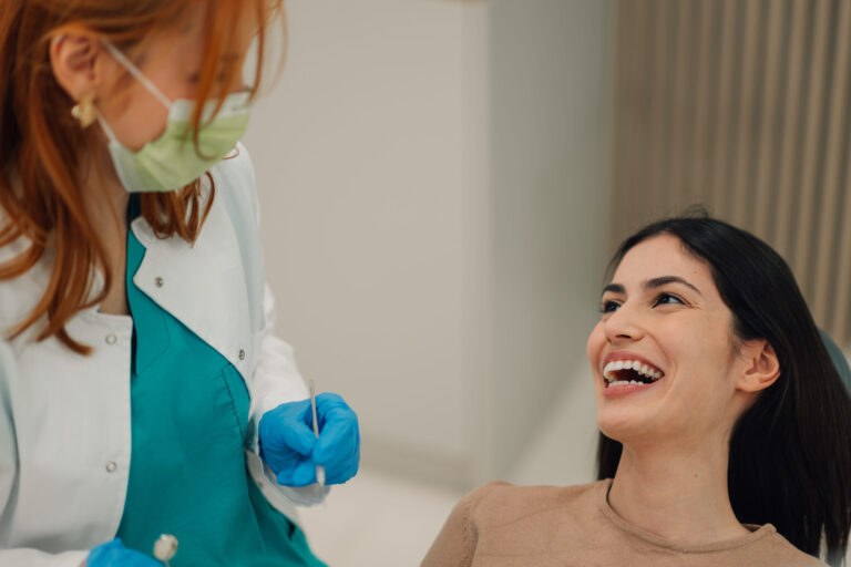 Female dentist performing dental check up on smiling patient