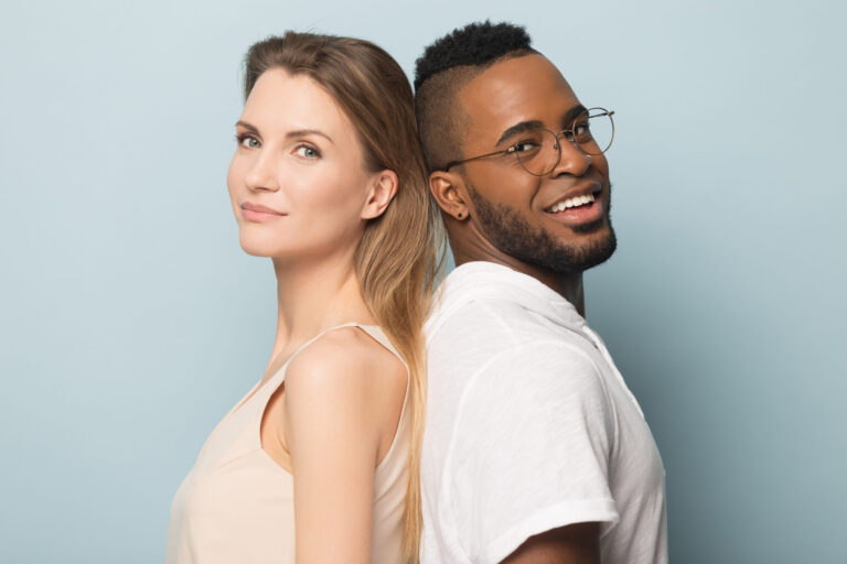 Smiling African American man and woman standing back to back